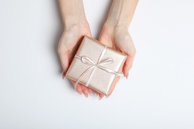 Gift in female hands on a colored background top view