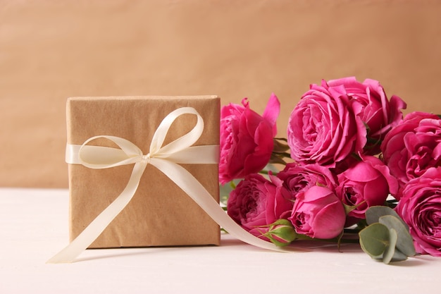 Gift and flowers on a colored background. Holiday, give a gift, congratulations. Valentine's Day, Mother's Day, International Women's Day. High quality photo