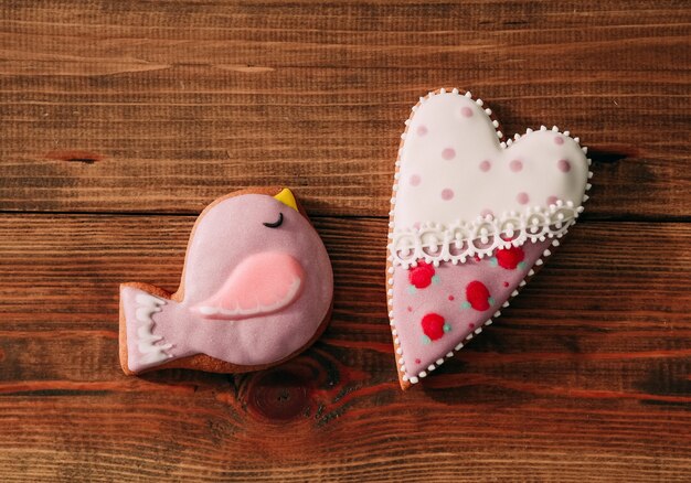 Gift gingerbread heart colored glaze wooden background center bird