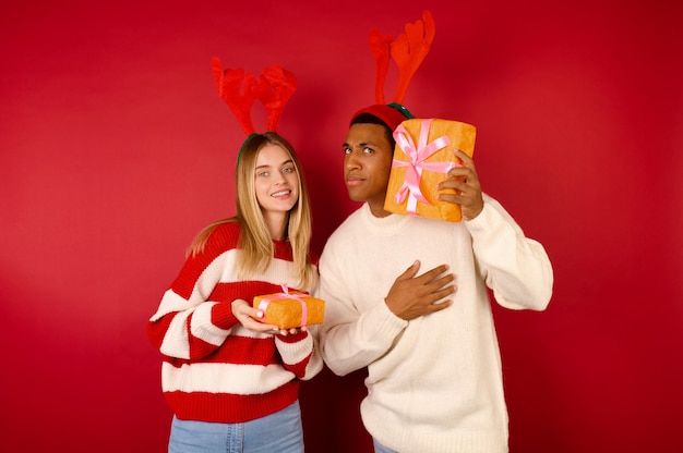 Gift-giving. A young coupe in reindeer hats holding gift boxes