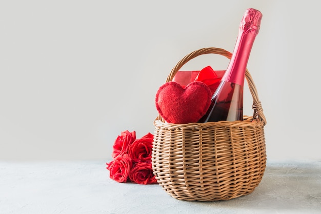 Gift hamper, bouquet of red roses,heart, bottle of champagne on white. Valentines day card. Romantic gift.