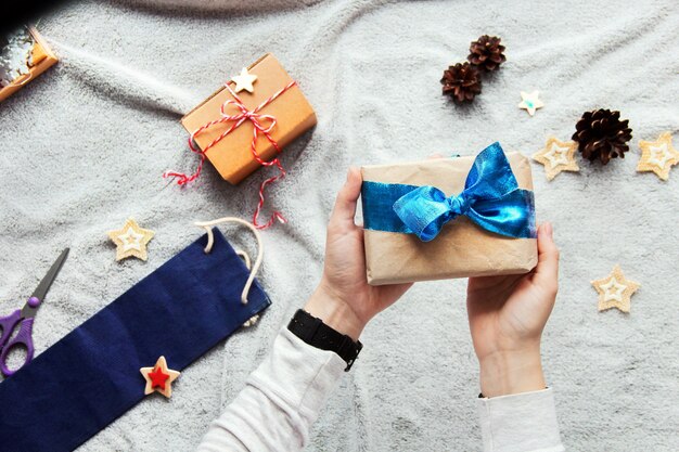 Gift in hand. gift wrapping process. blue bow. gifts in craft paper. festive atmosphere. new year's decor. minimalistic gift wrapping