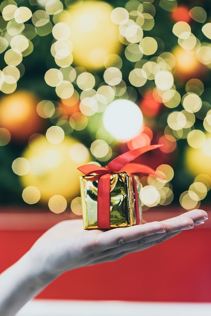 Regalo a portata di mano con sfondo chiaro di bokeh di natale