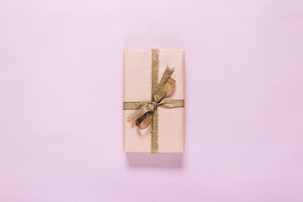 Gift in een doos met een gouden lint op een roze achtergrond