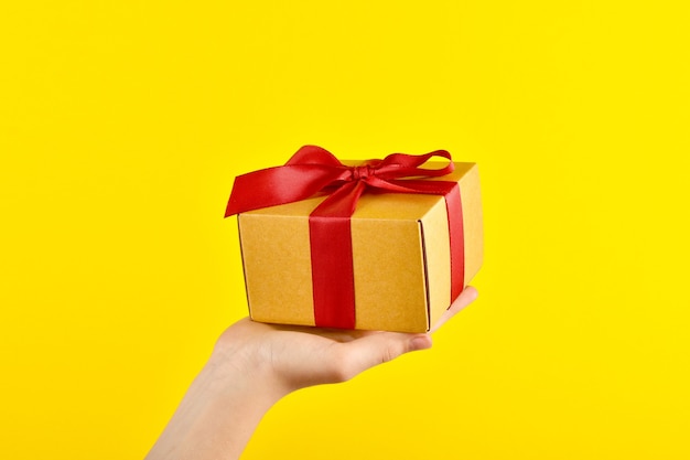 A gift is held on a yellow background. Delivery of orders