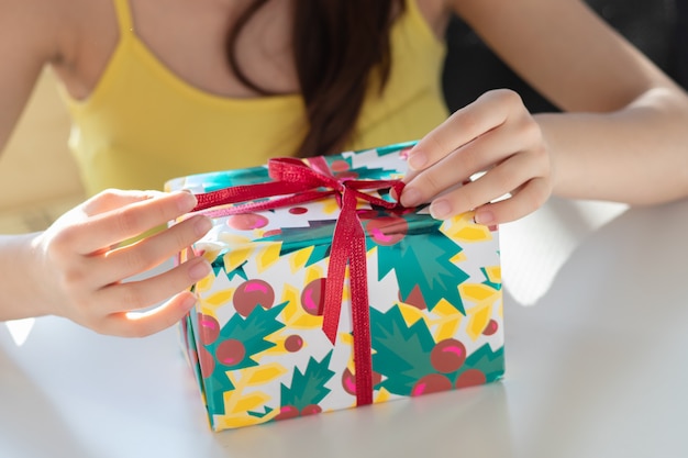 Gift for the new year. The girl opens the box with a gift, untie the ribbon, removes the wrapping paper