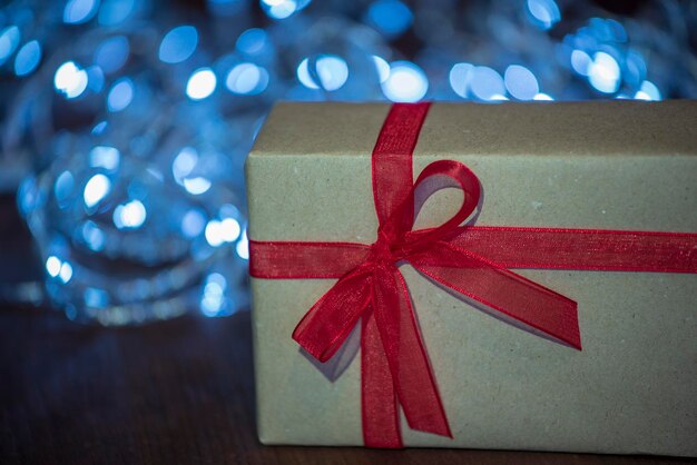 赤い弓とクリスマスライトの背景を持つギフトパッケージ