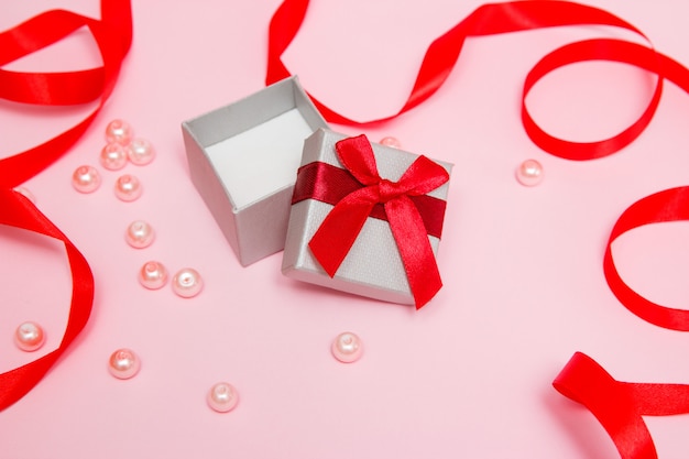 Gift on a pink background with beads and a red ribbon