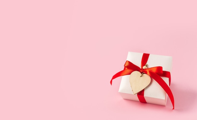 Photo gift or present box with red bow and heart on pink background.