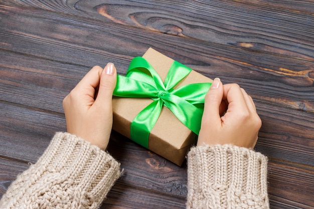 Gift or present with green bow. Woman hands showing and giving gifts.