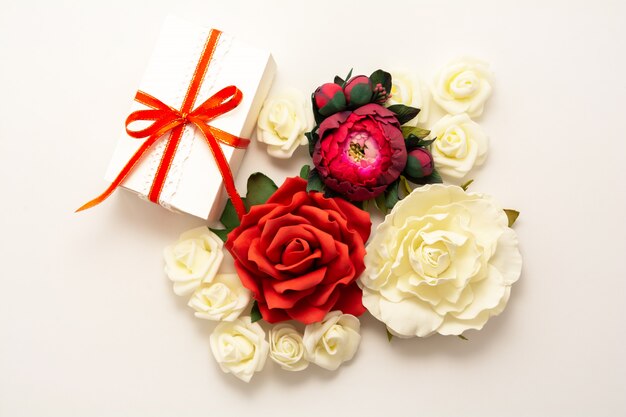 Gift, red ribbon, red and white flowers top view