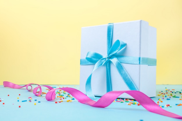 Gift, small box tied with a satin blue ribbon. Gift concept. Congratulations on holidays, give gifts.