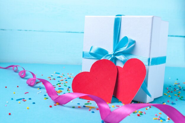 Gift, small box tied with a satin blue ribbon and red hearts. Gift concept. Surprises and gifts for loved ones. Congratulations on the holiday