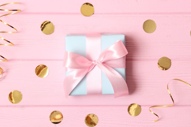 Подарок и блестки конфетти на цветном фоне минимализм вид сверху