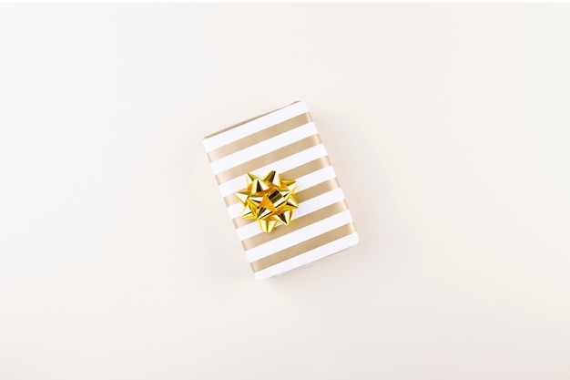 Gift in striped paper with golden bow . Top view.