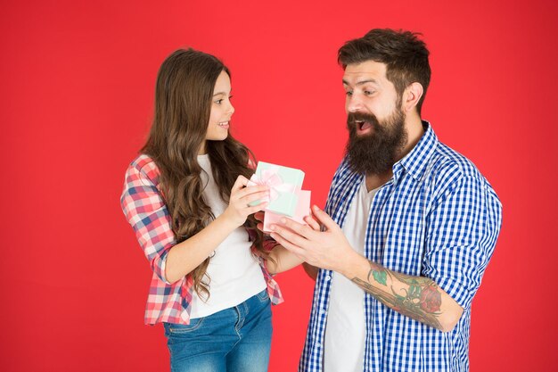 Foto sorpresa regalo. festa in famiglia. uomo barbuto padre e bambina carina figlia sfondo rosso. festeggia la festa del papà. i valori della famiglia concetto. relazioni amichevoli. padre hipster e sua figlia.