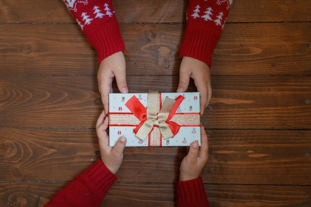 Photo gift in two kids hands on dark wooden background.