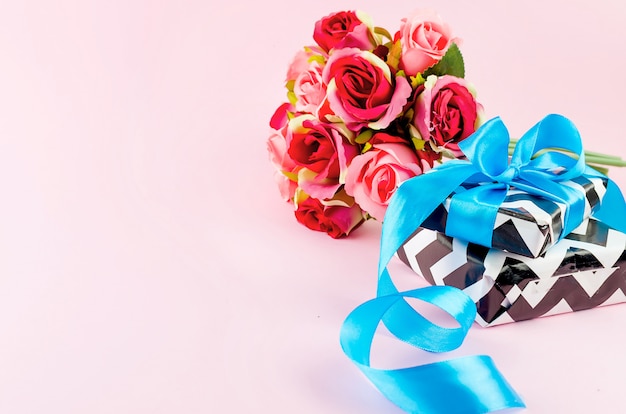 Gift with blue ribbon on a pink background