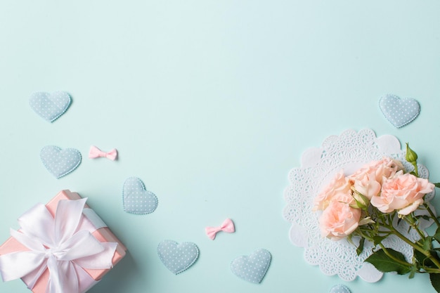 A gift with a bouquet of flowers and blue hearts on a light blue background