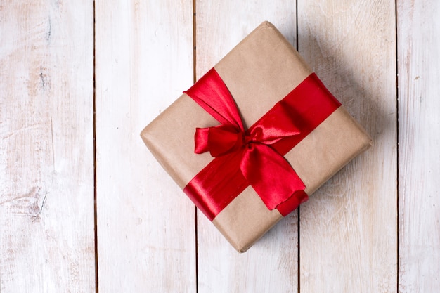 Gift with bow and kraft paper on a wooden background