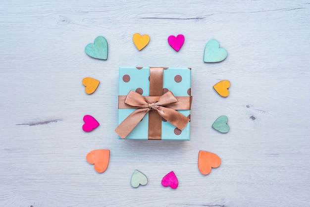 gift with bow on wooden table, with hearts