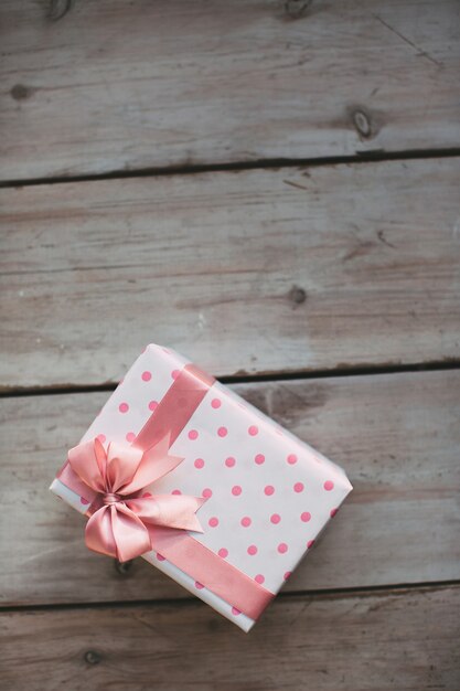 Gift with pink ribbon on the wood old table.