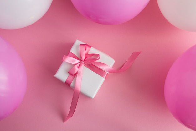 Photo gift with  pink and white balloons  on the pink surface.top view.