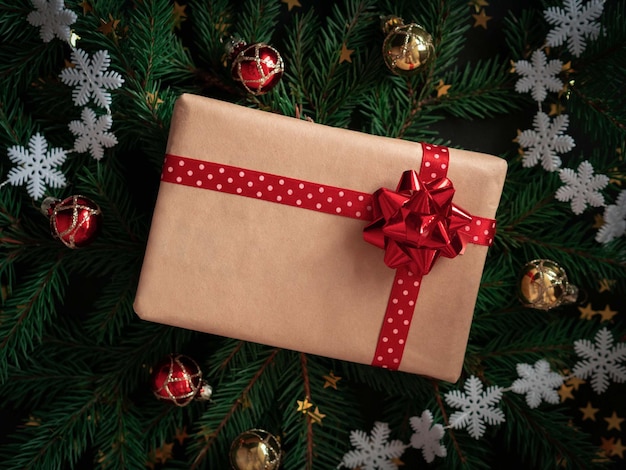 A gift with a red bow made of craft paper on a Christmas background with snowflakes and balloons