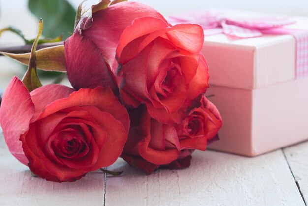 Gift with roses on wooden background