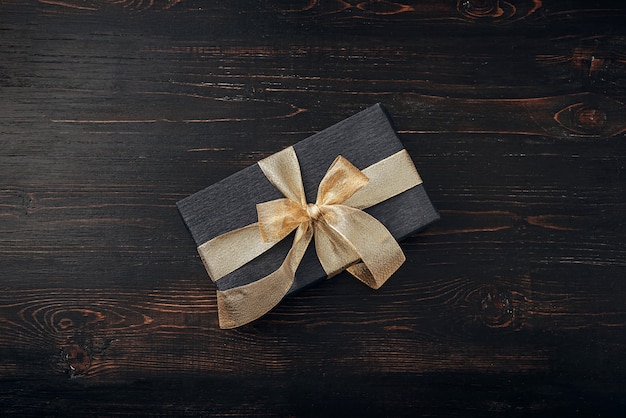 A gift wrapped in black paper and tied with a gold ribbon