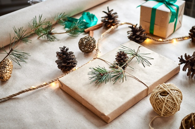 gift wrapping in craft paper tied with twine rope and decorated with a fir branch with a cone