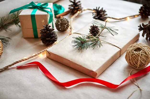 gift wrapping in craft paper tied with twine rope and decorated with a fir branch with a cone