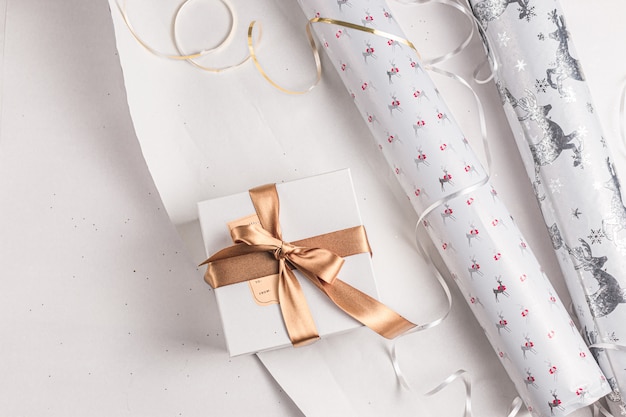 Фото Подарочная упаковка. праздничная оберточная бумага на рождество. белые, золотые, серебряные праздничные цвета. курортный сезон. упаковка подарочной коробки ручной работы.