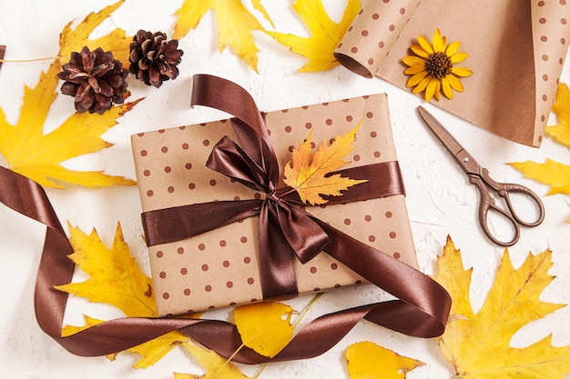 Gift Wrapping Handmade paper gift box with foliage dried leaves pine cones on white Autumn creative holiday present Thanksgiving day fall background