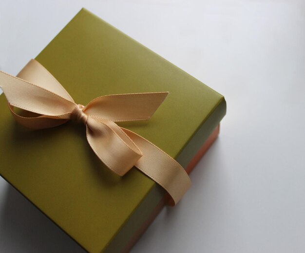 Gift wrapping in olive tones with an elegant beige ribbon on a clean white sheet of paper