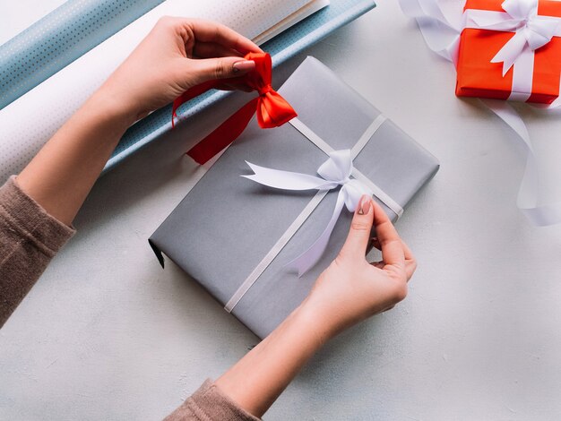 Gift wrapping. Woman hands decorating gift box