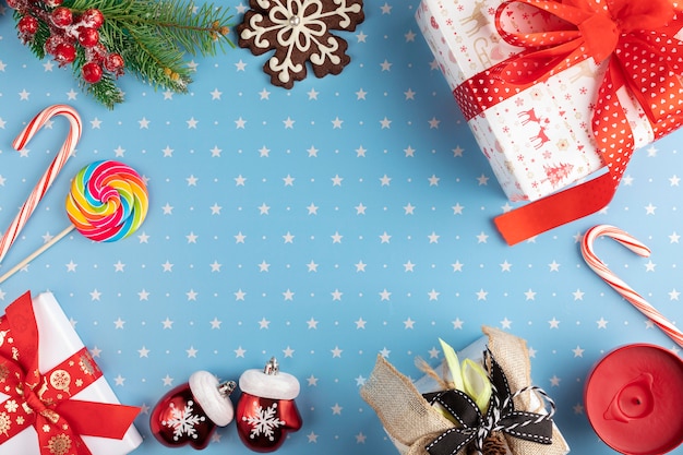 Foto giften, sparrentakken met rode bes, sneeuwvlokpeperkoek en snoepjes op blauwe achtergrond met patroon van sterren ... kerstmis, de winter, nieuw jaarconcept.