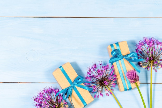 Gifts on a blue wooden background with purple flowers.