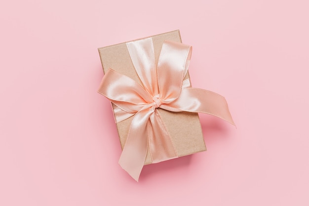 Gifts box with ribbon on pink surface