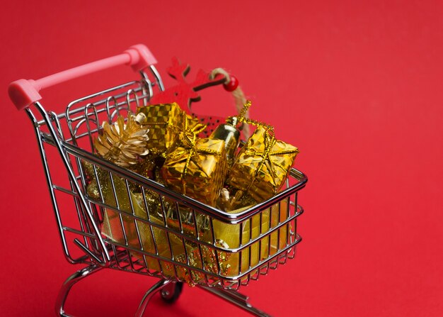 Gifts and christmas toys in a trolley on red