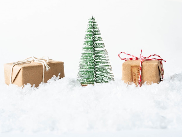 Gifts and Christmas tree in snow on white background. Merry Christmas or Happy New Year composition. Copy space