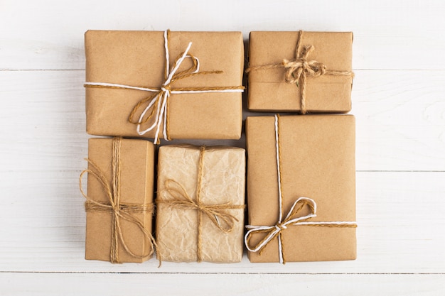 Gifts from Kraft paper lie tightly to each other on a white table