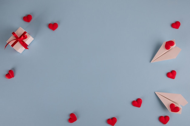 Gifts, hearts, paper planes on pastel blue table.