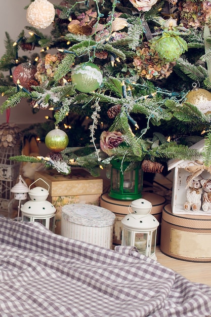 Gifts lie on a plaid blanket under the Christmas tree