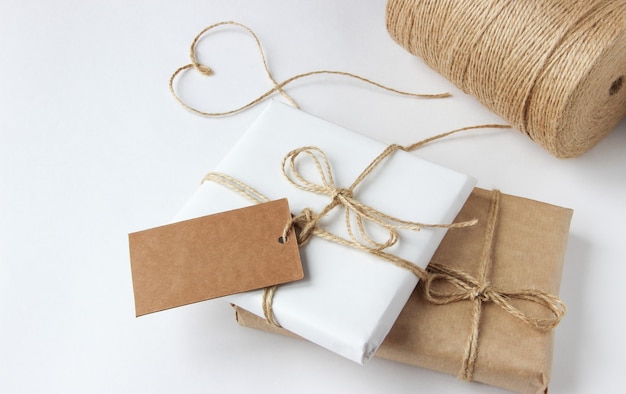 Gifts packed in kraft paper and white paper lie on a white table top view tag for copy space