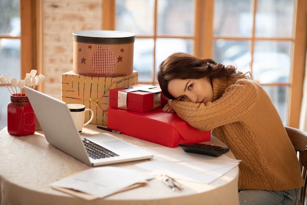 Gifts ready. Dark-haired young woman feeling tired after packing gifts