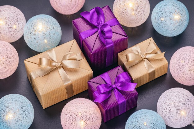 Gifts in smart packaging in boxes with ribbons and bows Luminous Christmas balls gray background