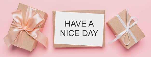 Gifts with note letter on isolated pink background, love and valentine concept with text HAVE A NICE DAY