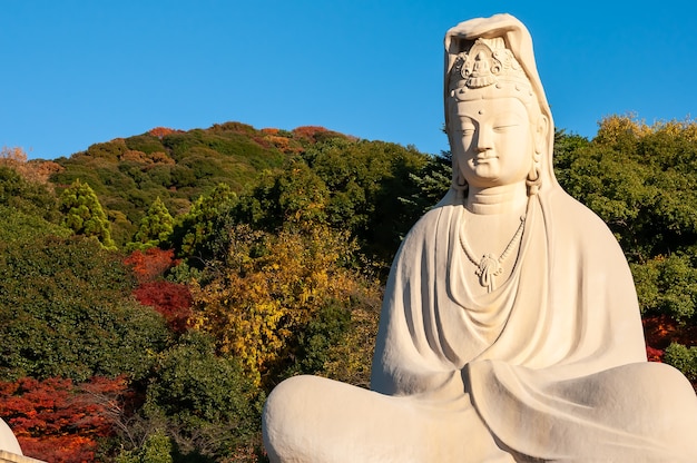 Gigantisch standbeeld van Ryozen Kannon Bodhisattva Avalokitesvara, verlicht door verbazingwekkend zonlicht, herfstbergen, blauwe lucht.