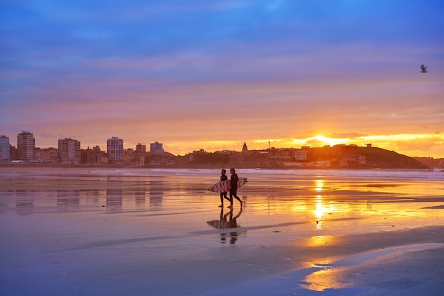 Foto tramonto di gijon surfisti della spiaggia di san lorenzo nelle asturie